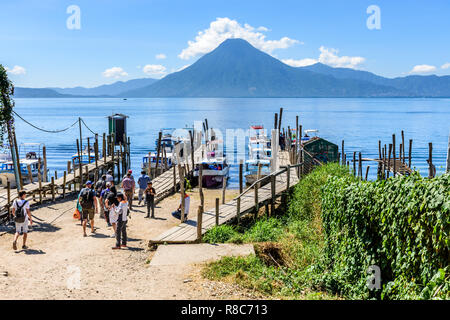 Panajachel, lago Atitlan, Guatemala - 12 Novembre 2018: la gente del posto e i turisti a piedi barche intitolata a villaggi sul lago con San Pedro vulcano dietro. Foto Stock