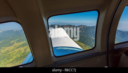 Splendida vista della gamma della montagna da una finestra di un piccolo aereo in fase di decollo. Il viaggio in aereo nelle isole Figi, Melanesia, Oceania. Il verde lussureggiante vegetazione su em Foto Stock