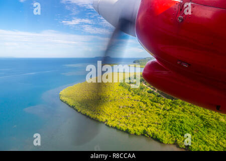 Il viaggio in aereo nelle isole Figi, Melanesia, Oceania. Vista di un verde remota isola tropicale da una finestra di un piccolo propulsore a turboelica motore rosso aereo Foto Stock