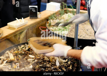 Un cuoco italiano a caldo di cottura di funghi selvatici risotto di farro in un mercato di Borough stallo nella parte sud di Londra Inghilterra REGNO UNITO KATHY DEWITT Foto Stock