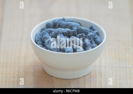 Caprifoglio Blue Berry(Honeyberries, woodbine, woodbind) sulla piastra bianca sul tavolo di legno Foto Stock