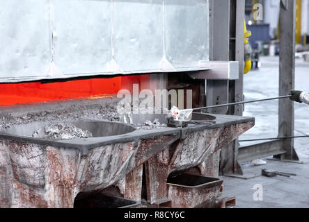 Un lavoratore il prelievo di un campione di alluminio fuso dall'interno di un forno di grande dressing il vestiario protettivo alluminò Foto Stock