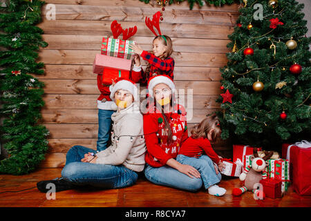 Bad kids e il padre e la madre legato con una ghirlanda vicino albero di Natale a casa Foto Stock