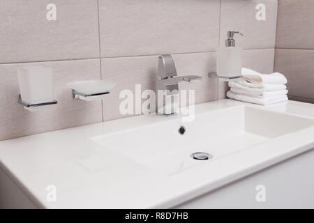 Epmty interni minimalisti sfondo, bagno di moderno appartamento, lavabo closeup e asciugamani in colori chiari, nessuno, con spazio copia, verticale Foto Stock