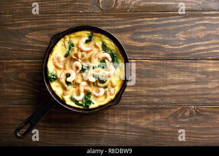 Funghi e spinaci frittata con gamberetti in padella su sfondo di legno con copia spazio. Vista superiore, laici piatta Foto Stock