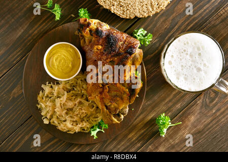 Arrosto di maiale il fuso a snodo (eisbein) con brasato di cavolo (crauti) e birra su di un tavolo di legno. Vista superiore, laici piatta Foto Stock