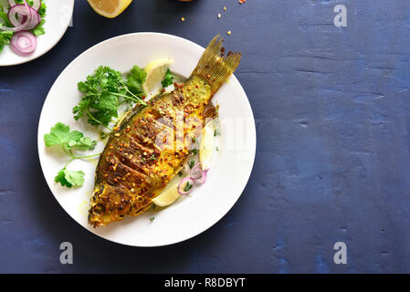 Pesce arrosto su piastra su pietra blu sfondo con copia spazio. Vista superiore, laici piatta Foto Stock