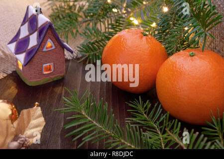 Tangerini (clementine) e ornamenti con le luci di Natale e rami di abete su sfondo di legno Foto Stock