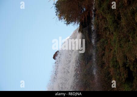 Sharp close up di acque bianche - in chiaro, linee dritte - sgorga sopra il bordo di una scogliera in un crollo drammatico, cascata Foto Stock