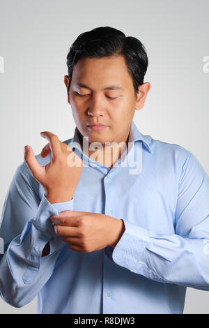 Immagine fotografica di un bel attraente giovane imprenditore asiatici medicazione, pulsante in alto la sua manica. Preparazione di nozze. Pronto a lavorare in abbigliamento formale Foto Stock