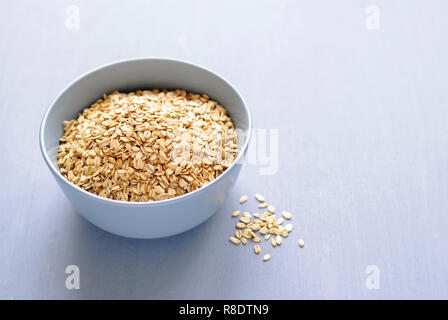 Ceramica grigia ciotola di farina d'avena a secco su uno sfondo grigio con un'ombra, visualizzate in primo piano da elevato angolo con spazio di copia Foto Stock