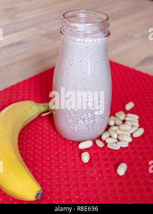 Banana e frullato di arachidi su un rosso tabella mat Foto Stock