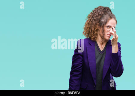 Bruna giovane studente bambina indossa uniformi scolastiche e bicchieri su sfondo isolato annusare qualcosa di maleodorante e disgustoso, intollerabile odore, h Foto Stock