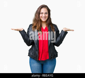 Bella la dimensione più giovane donna che indossa una moda giacca di pelle su sfondo isolato sorridente che mostra entrambe le mani aperte le palme, presentazione e pubblicità Foto Stock