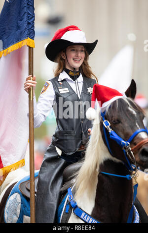 Houston, Texas, Stati Uniti d'America - 22 novembre 2018 l'H-E-B la Giornata del Ringraziamento Parade, una donna con il Sheriff badge e uniforme in sella ad un cavallo con un cappello di Natale Foto Stock