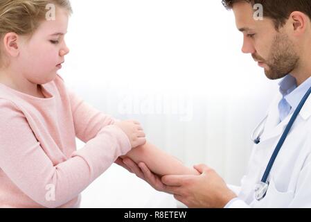 Medico maschio esaminando la ragazza braccio. Foto Stock