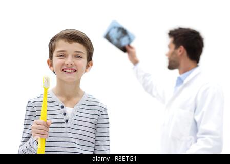 Ragazzo azienda per dimensioni uno spazzolino da denti in chirurgia dentale, con medico azienda apparecchiature odontoiatriche a raggi x. Foto Stock