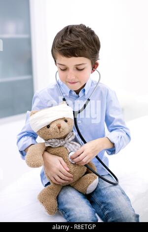 Ragazzo giochi di ruolo con Teddy bear e stetoscopio. Foto Stock