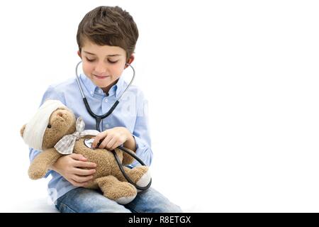 Ragazzo giochi di ruolo con Teddy bear e stetoscopio. Foto Stock