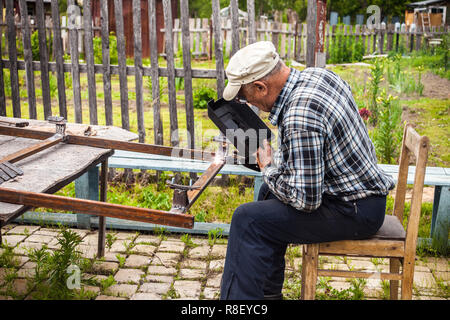 Senior uomo saldatura struttura metallica al suo giardino Foto Stock
