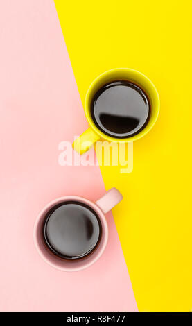 Lay piatto vista dall'alto di due tazze da caffè con rosa e giallo. Foto Stock