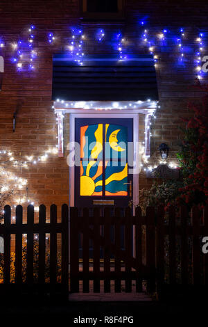 Sole e Luna porta a vetri colorati e le luci di Natale su una casa in Bloxham. Bloxham, Oxfordshire, Inghilterra Foto Stock