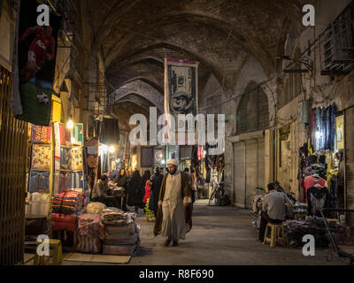 ISFAHAN, IRAN - 20 agosto 2018: l'Islam passando sotto un asciugamano conformata come un dollaro statunitense bill in Isfahan bazar di sera. Il rial iraniano, Iran Foto Stock