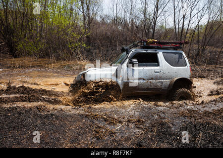 Suzuki Jimny attraversando acqua ostacolo nella foresta di primavera Foto Stock