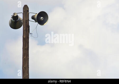 Indirizzo pubblico Avvisatore acustico altoparlanti sul palo di legno sopra il cielo blu.