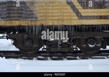 Foto dettagliate di una vettura congelate di treni passeggeri con ghiaccioli e ghiaccio sulla sua superficie. Stazione ferroviaria nella fredda stagione invernale Foto Stock