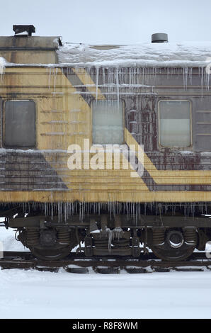 Foto dettagliate di una vettura congelate di treni passeggeri con ghiaccioli e ghiaccio sulla sua superficie. Stazione ferroviaria nella fredda stagione invernale Foto Stock