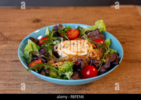 Un insalata con formaggio di capra, cipolla, arachidi, pomodorini e condimento Foto Stock