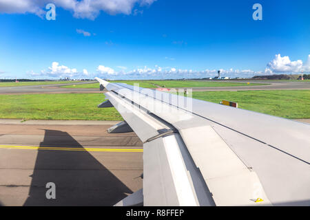 Ala da finestra della vista aereo durante il piano di sbarco o prima del decollo in modo taxi in aeroporto con cielo blu chiaro in Francia Foto Stock