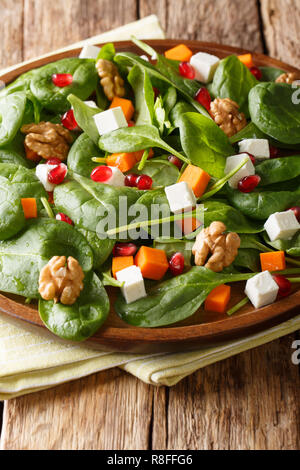 In casa di zucca, insalata di spinaci freschi, il formaggio feta, le noci e i semi di melograno closeup su una piastra sul piano verticale. Foto Stock