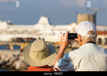 Rhodes, Grecia - Ottobre 10th, 2018: una coppia senior turisti scattare foto con una piccola fotocamera digitale presso il porto di Rodi, Grecia. Foto Stock