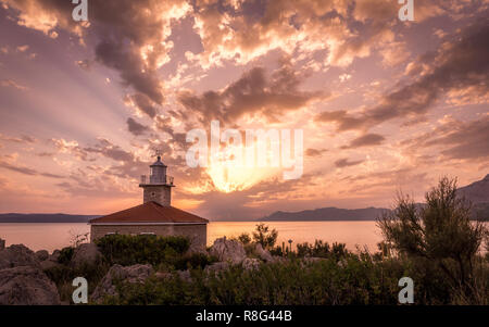 Bellissimo tramonto sul mare Mediterraneo con il faro in primo piano a Makarska, Croazia Foto Stock