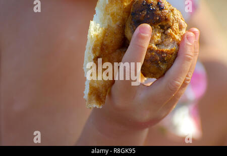 Deliziosi hamburger, nelle mani di un bambino. Burger con cotoletta, cetriolo sottaceto, lattuga, pomodori, formaggi, salsa di sesamo bun e fettine di carne. Fast Foto Stock