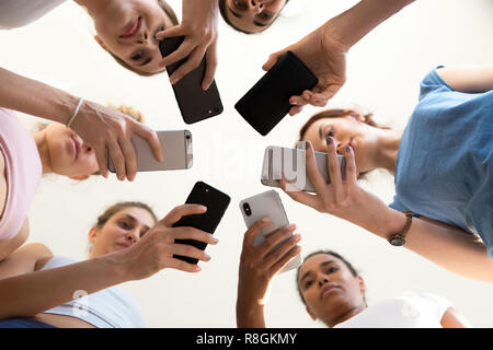 Diverse le femmine in piedi in cerchio gli smartphone di contenimento vista dal Foto Stock