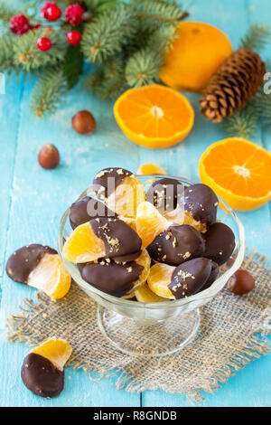Fette di mandarini in cioccolato. Il dessert Tangerini su un tavolo di legno. Foto Stock