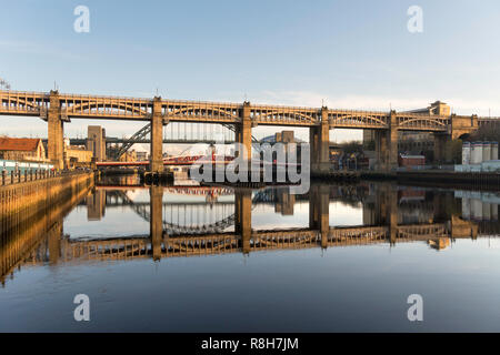 Il livello alto ponte e Tyne Bridge si riflette nel fiume, Newcastle upon Tyne, England, Regno Unito Foto Stock