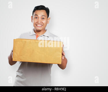 Foto immagine ritratto di un simpatico bel giovane corriere asiatico uomo sorridente mentre dando confezione regalo scatola in dovere di consegna Foto Stock