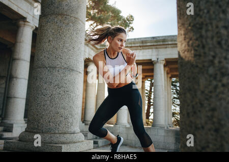 donna che fa esercizi aerobici in piedi vicino a pilastri di pietra. Donna che fa danza aerobica come parte dell'allenamento fitness. Foto Stock