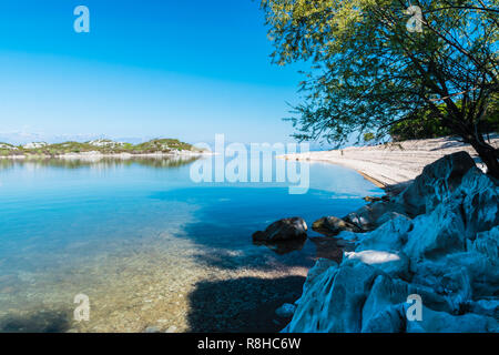 Bianco ricerca tropicale spiaggia con rocce bianche, gli alberi e le montagne in de background a Lago di Skadar, Montenegro durante il giorno asunny in primavera. Foto Stock