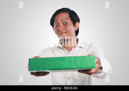 Foto immagine ritratto di un divertente giovani asiatici uomo sorridente felicemente con grandi occhi aperti mentre dando verde regalo scatola di imballaggio Foto Stock