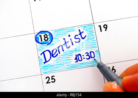 Dita di donna con penna scrittura dentista promemoria 10-30 in calendario. Close-up. Foto Stock
