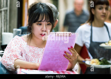 Croazia, Split - Settembre 22th, 2018: una femmina clienti asiatici seduti all'aperto in un ristorante in cerca di un menu. Foto Stock