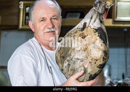 Croazia, Split - Settembre 22th, 2018: un venditore maschio che mostra orgoglioso un maiale prosciutto nel suo negozio. Foto Stock