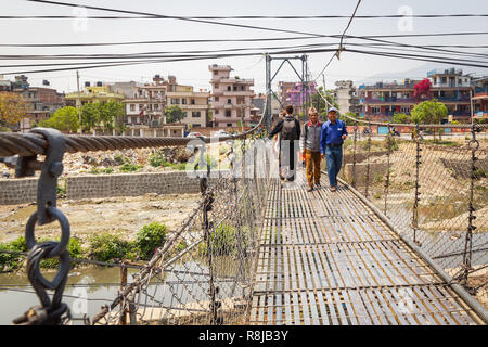 Gli uomini a camminare su una sospensione ponte sul fiume Bagmati a Kathmandu in Nepal Foto Stock
