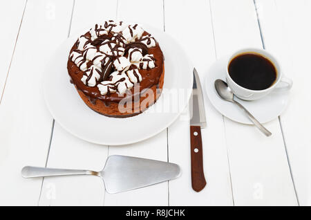 Torte fatte in casa con souffle di cioccolato decorate con marshmallow e tazza di caffè nero su bianco tavolo in legno Foto Stock