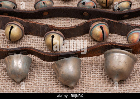 Antique vintage ossidare ottone sleigh bells sul cinturino in pelle e tela sfondo Foto Stock